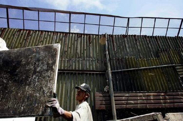 En arbejder er i gang med at reparere det metalhegn, som de amerikanske myndigheder har sat op mellem Mexico og USA for at holde indvandrere ude. - Foto: AP 