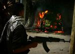 En palæstinsisk politmand går fordi en brændende bil i Gaza i dag, hvor politiet var i kamp mod Hamas-folk. - Foto: AP 