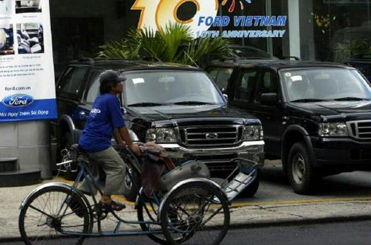 Et vietnamesisk cykelbud kører forbi den amerikanske bilkoncern Fords lokaler i Ho Chi Minh by. I dag er en historisk samhandelsaftale underskrevet mellem de to lande. - Foto: AP 