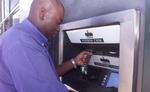 En zimbabwer forsøger at hæve penge i en automat i Harare. På grund af akut mangel på penge udsteder regeringen nu en 100.000 dollar seddel. - Arkivfoto: AP 