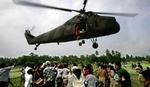 Overlevende fra jordskælvet i Bantul i Indonesien flokkes om en helikopter for at få fat i pakker med fødevarehjælp. - Foto: AP 