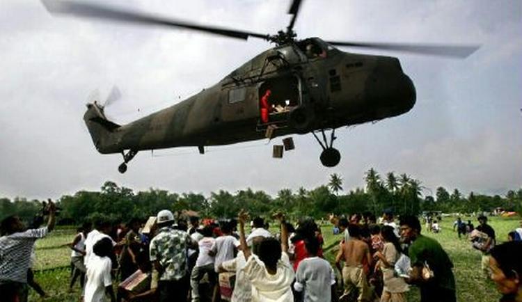Overlevende fra jordskælvet i Bantul i Indonesien flokkes om en helikopter for at få fat i pakker med fødevarehjælp. - Foto: AP 
