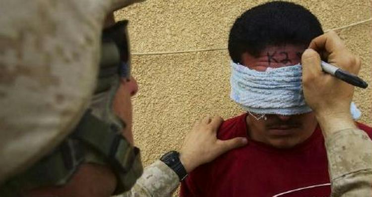 En amerikansk marine-infanterist i gang med at 'mærke' en irakisk fange i byen Haditha. - Foto: AP 