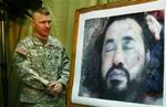 En amerikansk soldat står ved en fotostat med billedet af den dræbte al-Qaeda-leder i Irak, Abu Musab al-Zarqawi. - Foto: AP 