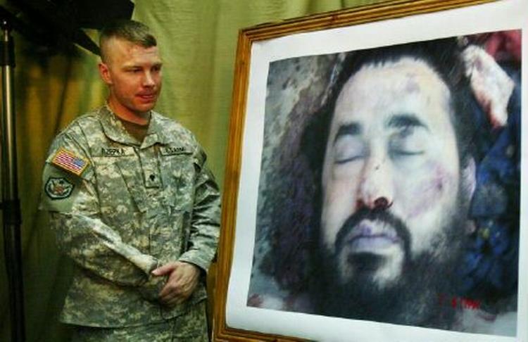En amerikansk soldat står ved en fotostat med billedet af den dræbte al-Qaeda-leder i Irak, Abu Musab al-Zarqawi. - Foto: AP 