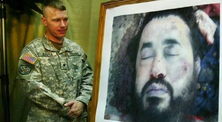 En amerikansk soldat præsenterer umiddelbart efter luftangrebet i Baluqa et billede af den døde terrorleder - for hurtigst muligt at overbvise pressen om, at det virkelig var Zarqawi. - Foto: AP 