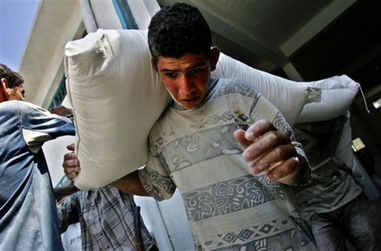 FN distribuerer fødevarer i Gaza. Her slæber en dreng af sted med en sæk mel.   Foto: Kevin Frayer/AP 