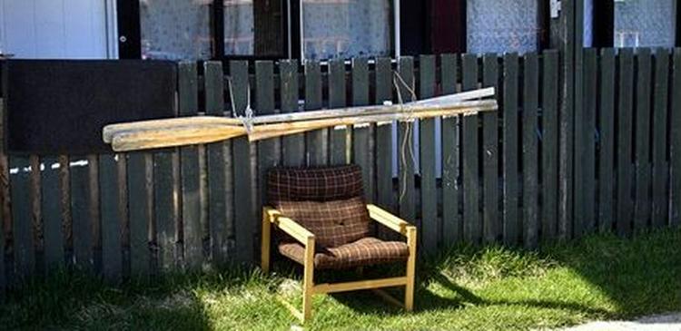 POLARSOMMER. Ovre i træbarakkerne på Ceresvej har en pensionist trukket tv-stolen ud i det fri, og de frækkeste unger dypper tæerne i det iskolde hav.   Foto: Christian Graugaard 