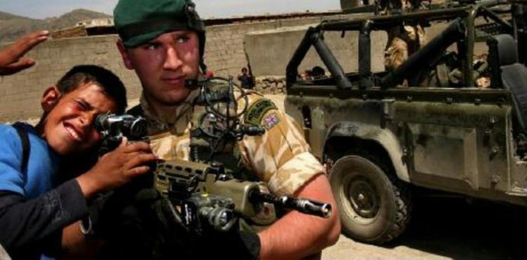 En afghansk skoleelve kigger igennem en kikkerten på en britisk soldats gevær. - Foto: AP 