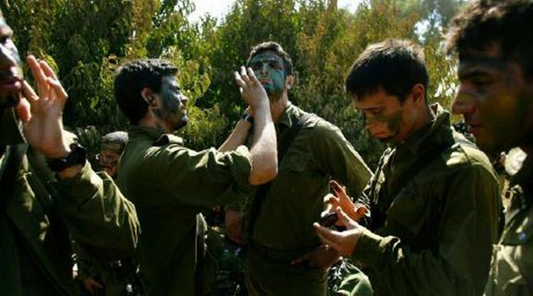 Israelske soldater lægger camouflage, inden de skal krydse grænsen til Libanon. Kampene om Bint Jbeil i det sydlige Libanon har kostet Israel store tab. - Foto: AP 