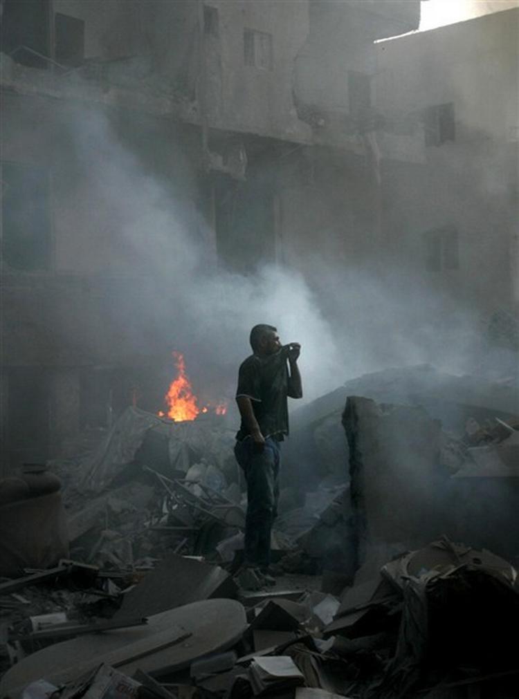 Et af målene i går for de israelske kampfly var centrum af den libanesiske kystby Tyre, hvor en mand i minutterne efter fuldtræfferne, prøvede at beskytte sig imod røgen, mens kan prøvede at få et overblik over ødelæggelserne.   Foto: AP 
