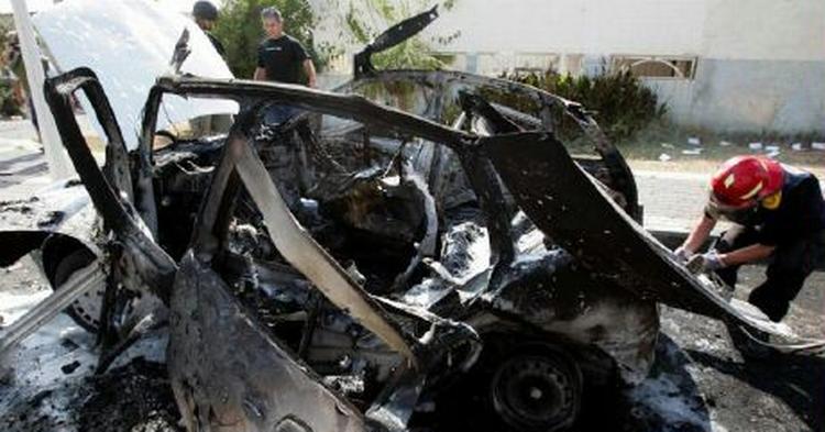 Israelske brandfolk arbejder ved en bil, som i dag blev ramt af en Hizbollah-raket i byen Nahariya ved grænsen til Libanon. - Foto: AP 