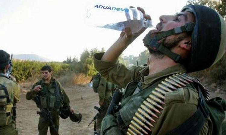 En israelsk soldat drikker vand, efter at være vendt tilbage over grænsen til Libanon - Foto: AP 