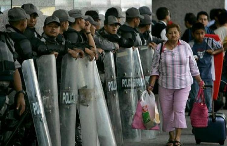 Politi forsøger at lægge en blokade mellem stridende demonstranter i Mexico. - Foto: AP 