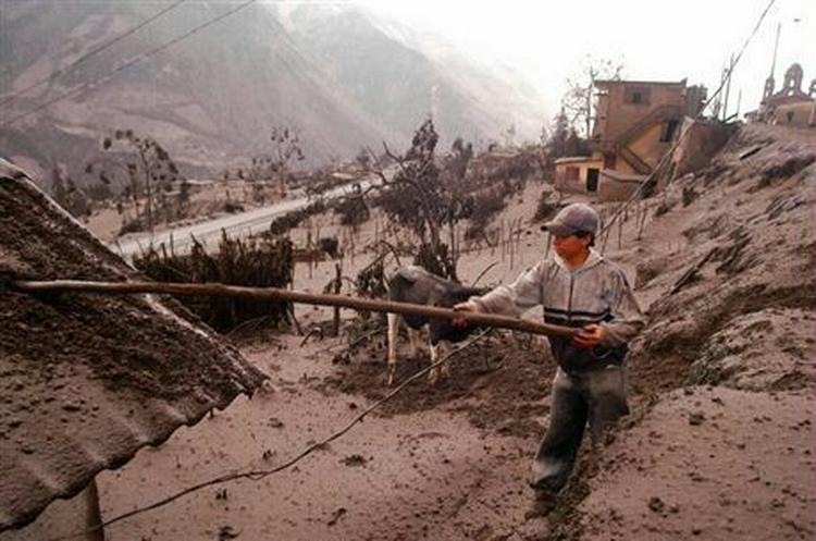 En dreng børster vulkansk aske af et hustag i Banos, Ecuador. - Foto: AP 