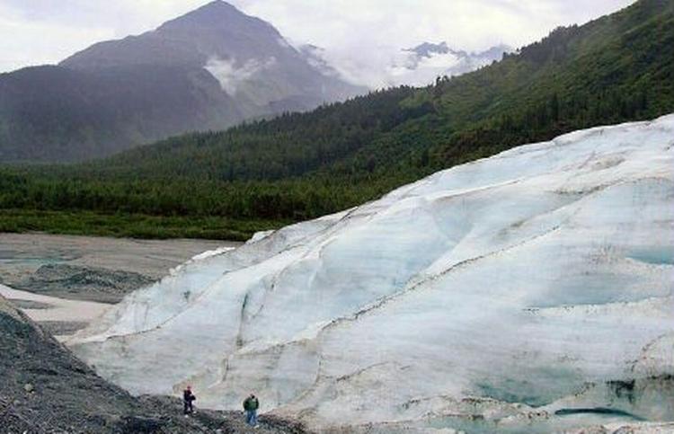 To personer passerer en gletscher i Alaska. Det viser sig, at gletscherne over lang tid har trukket sig langsomt tilbage. - Arkivfoto: AP 