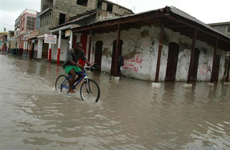 En mand cykler igennem en oversvømmet gade i Haitis hovedstad Port-au-Prince. 