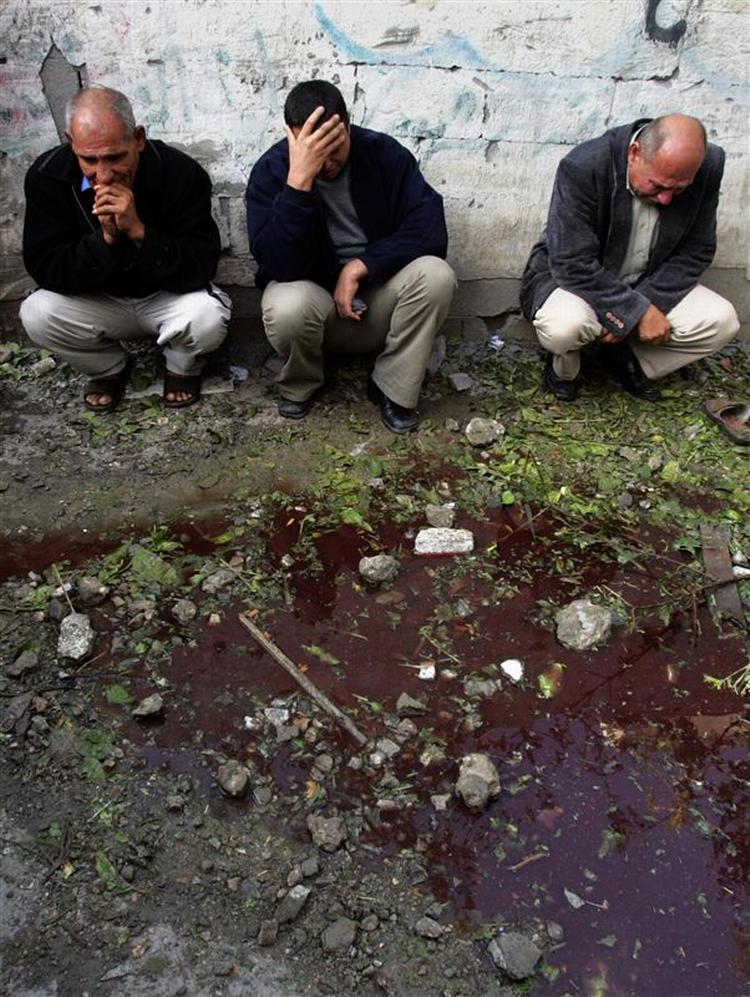 Palæstinensere sidder ved en pøl af blod og vand i Beit Hanoun efter det israelske angreb. 