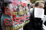 A Korean War veteran sits next to a poster featuring North Korean Leader Kim Jong Il, left, South Korean President Roh Moo-hyun, center, and former President Kim Dae-jung during an anti-government rally against North Korea's nuclear program, in Seoul, Friday, Nov. 10, 2006. Chief envoys from South Korea, Japan and the United States will discuss North Korea's nuclear program on the sidelines of an Asia-Pacific Economic Cooperation meeting next week in Vietnam, the Yonhap news agency said Friday. The letters read "Abolition of June 15 inter-Korean Joint Declaration and resignation of President Roh Moo-hyun."  (AP Photo/ Lee Jin-man) 