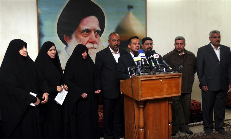 En flok af al-Sadr-støtter lyttede, mens Salih al-Igeili (midt for) læste deres protesterklæringen op.Plaketen bagved forestiller Mohammed Sadiq al-Sadr, Muqtada al-Sadr's afdøde far. 