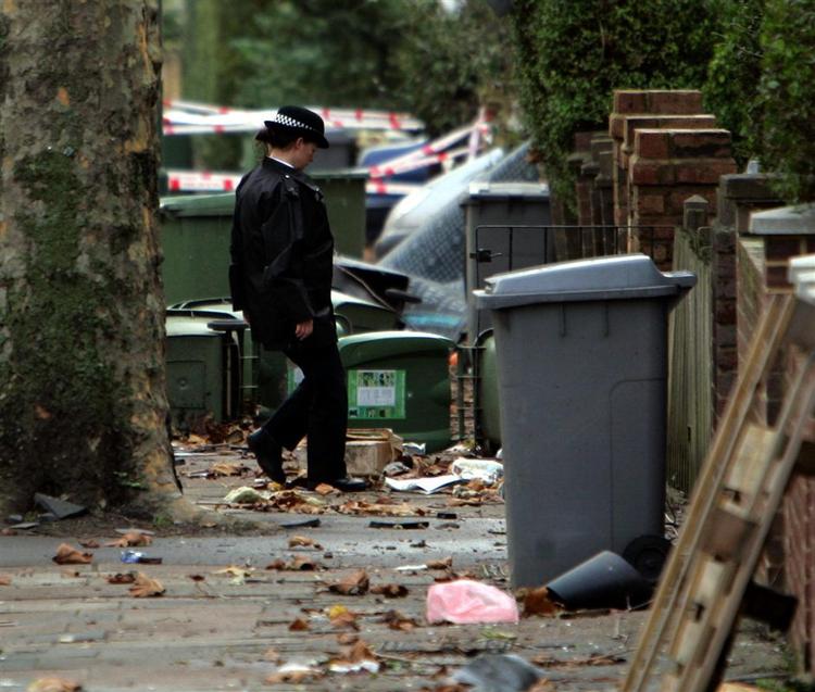 En britisk politibetjent går igennem en gade, hvor alt er væltet af tornadoen. 