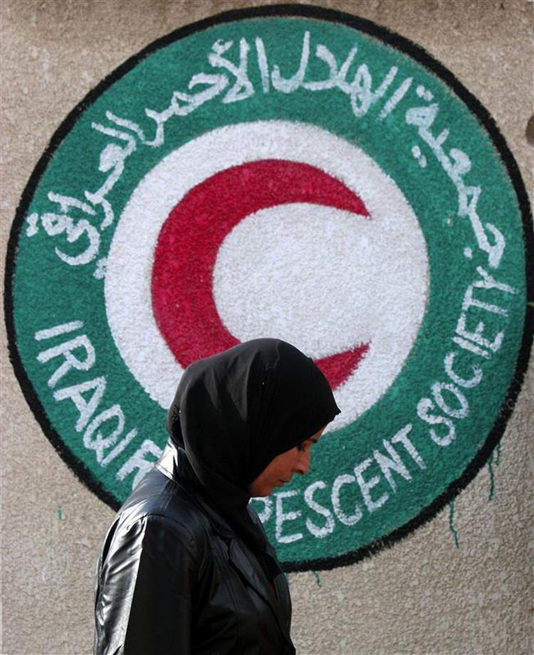 En irakisk kvinde, hvis slægtning var blandt de 30 mennesker, der blev kidnappet fra organisationens kontorer i Bagdad, går forbi den røde halvmåne, der symboliserer Røde Kors i Irak. 
