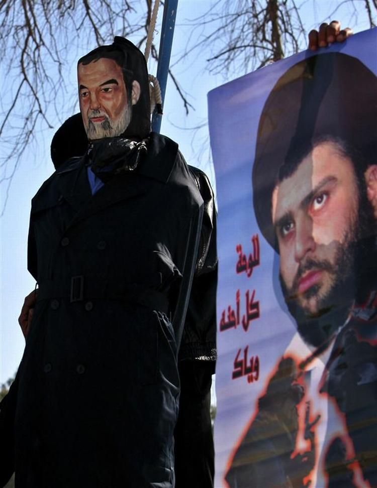 En dukke-kopi af Saddam Hussein 'hænges' ved siden af billede af den shiamuslimske præst Muqtada al-Sadr i Basra. 