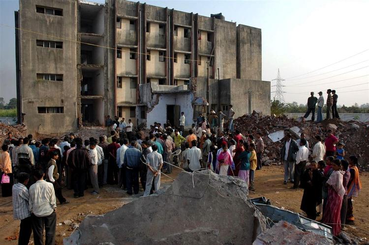 Folk samler sig om den sammenfaldne skole i byen Tichakpura i den indiske Gujarat-provins. Mindst 11 piger er dræbt ved ulykken. 