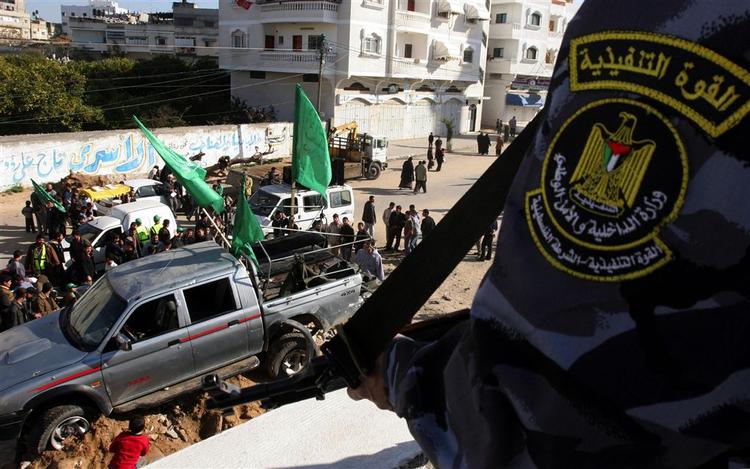 Folk samles om en lastbil fra Hamas’ sikkerhedsstyrker efter den i går blev beskudt. I forgrunden ses et medlem af sikkerhedsstyrkerne. 