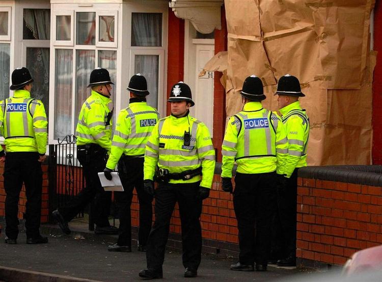 Politiet holder vagt uden for en af de 12 adresser i Birmingham, som i dag blev ransaget. 