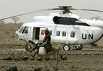 En kvinde, ridende på et æsel, passerer en helikopter med vandforsyninger. 