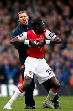En hidsig Emmanuel Adebayor 'får hjælp' til at forlade banen af en Arsenal-leder. 