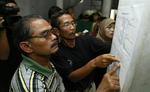 Pårørende på et hospial i Jakarta tjekker en liste med navne på de omkomne efter færgebranden. 