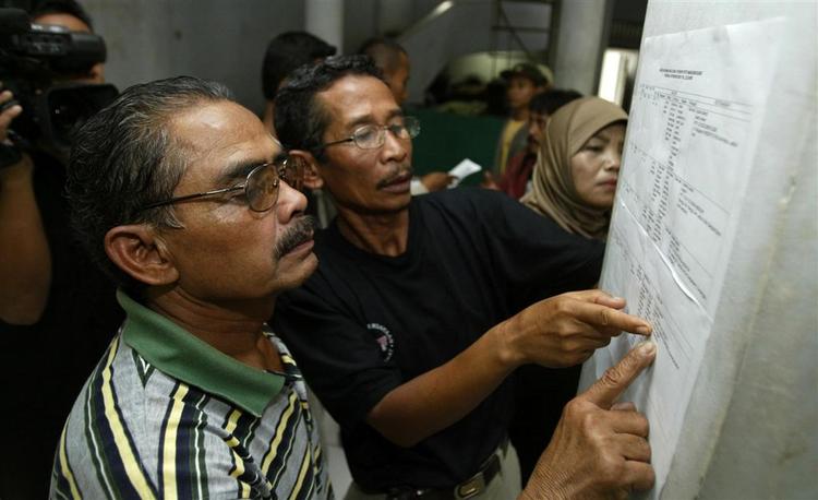 Pårørende på et hospial i Jakarta tjekker en liste med navne på de omkomne efter færgebranden. 