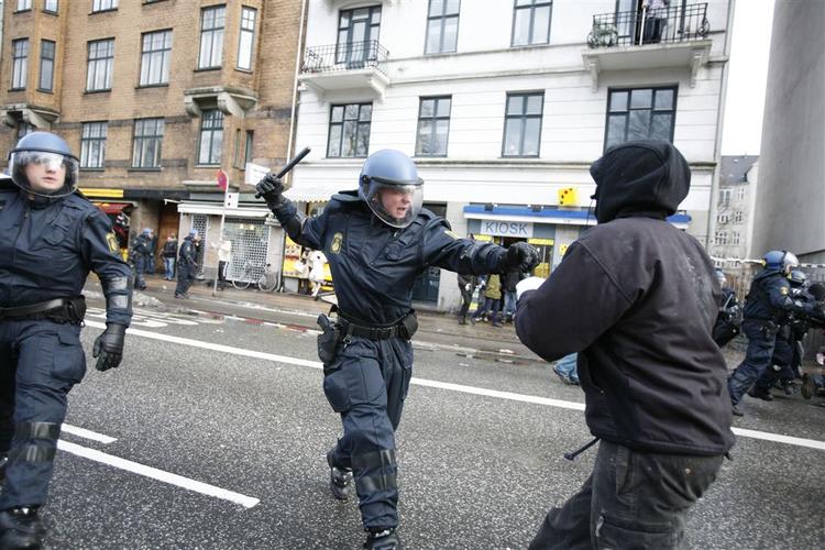 Politibetjent trækker staven for at holde demonstranter væk på Nørrebro efter morgenens rydning af Ungdomshuset. 