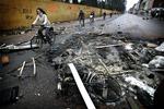 Cyklister på Nørrebrogade sniger sig forbi resterne af udbrændte containere og stjålne ting fra kælderrum. 