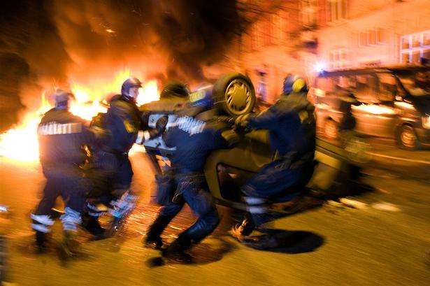 Betjente forsøger at fjerne en væltet privatbil fra Nørrebrogade. 