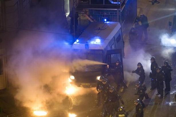 Politiet begynder at affyre tåregas mod demonstranterne, som har bevæbnet sig med brandbomber. 