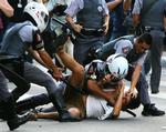 Brasiliansk politi tumler en demonstrant under tumulterne. 