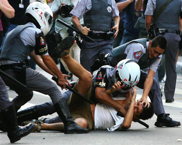 Brasiliansk politi tumler en demonstrant under tumulterne. 