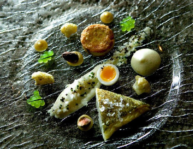 En forret på restaurant Ti Trin Ned i Fredericia: som små planeter på en stor himmel ligger sandart, bagt rogn, blomkål, nøddesmør, vagtelæg og nødder på tallerken. 