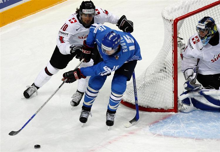 Finlands Tuomo Ruutu(i blåt) kæmper om pucken med Andres Ambuh(t.v.) og målmand Jonas Hiller fra Schweiz. 