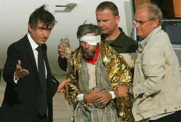 Den frigivne fange Eric Damfrevill med bind for øjet blev hjulpet på vej fra af den franske udenrigsminister Philippe Douste-Blazy til venstre i billedet, da flyet landede uden for Paris i dag. 