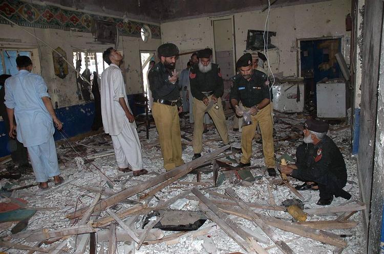 Pakistansk politi undersøger hotellet i Peshawar efter en bombe har slået mindst 24 mennesker ihjel. 