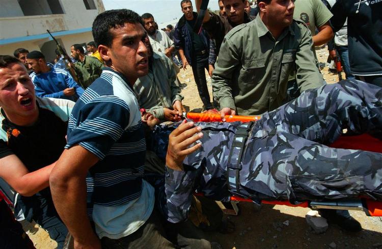 Palæstinensere bærer en såret soldat fra sikkerhedsstyrken i Hamas væk fra Gazas uroligheder. 