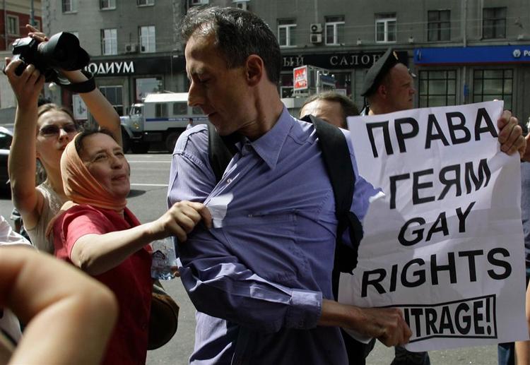 En kvinde iklædt traditionelt ortodokst tørklæde griber fat i den britiske aktivist Peter Tatchell på gaden i Moskva. 