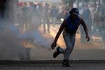 En demonstrant samler en tåregasgranat op i forbindelse med demonstrationer i Venezuelas hovedstad, Caracas, i går. 