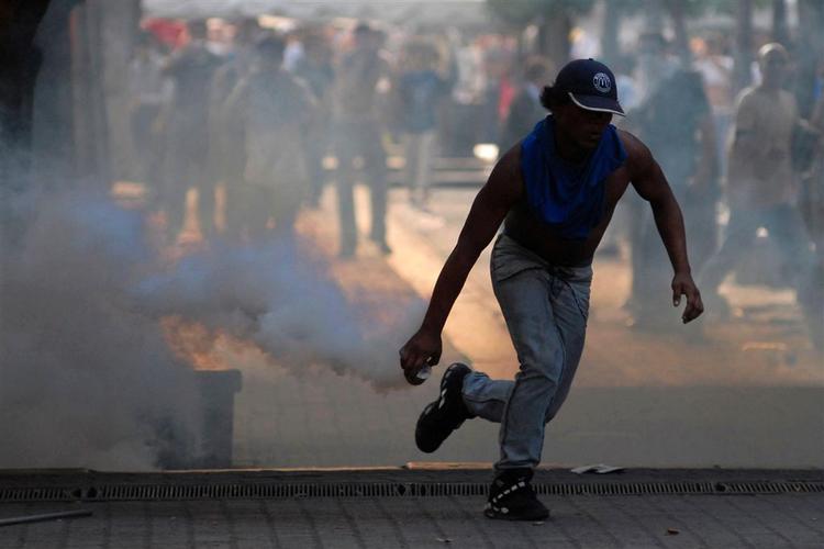 En demonstrant samler en tåregasgranat op i forbindelse med demonstrationer i Venezuelas hovedstad, Caracas, i går. 
