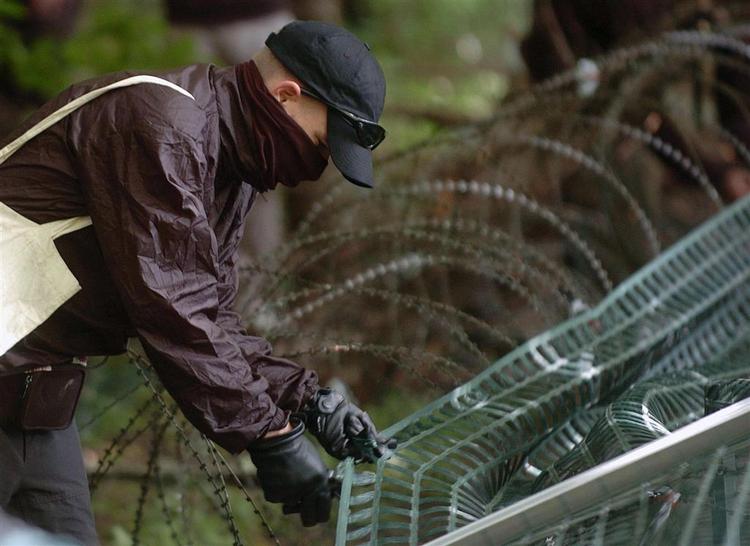 Demonstrant forsøger at klippe hul i sikkerhedshegnet rundt om G8-topmødet. 