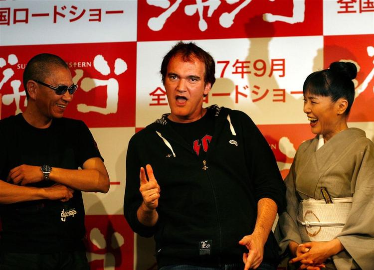 Den amerikanske filminstruktør og skuespiller Quentin Tarantino i midten lader som om, han skyder med pistoler på en pressekonference i Tokyo 11. juni. 